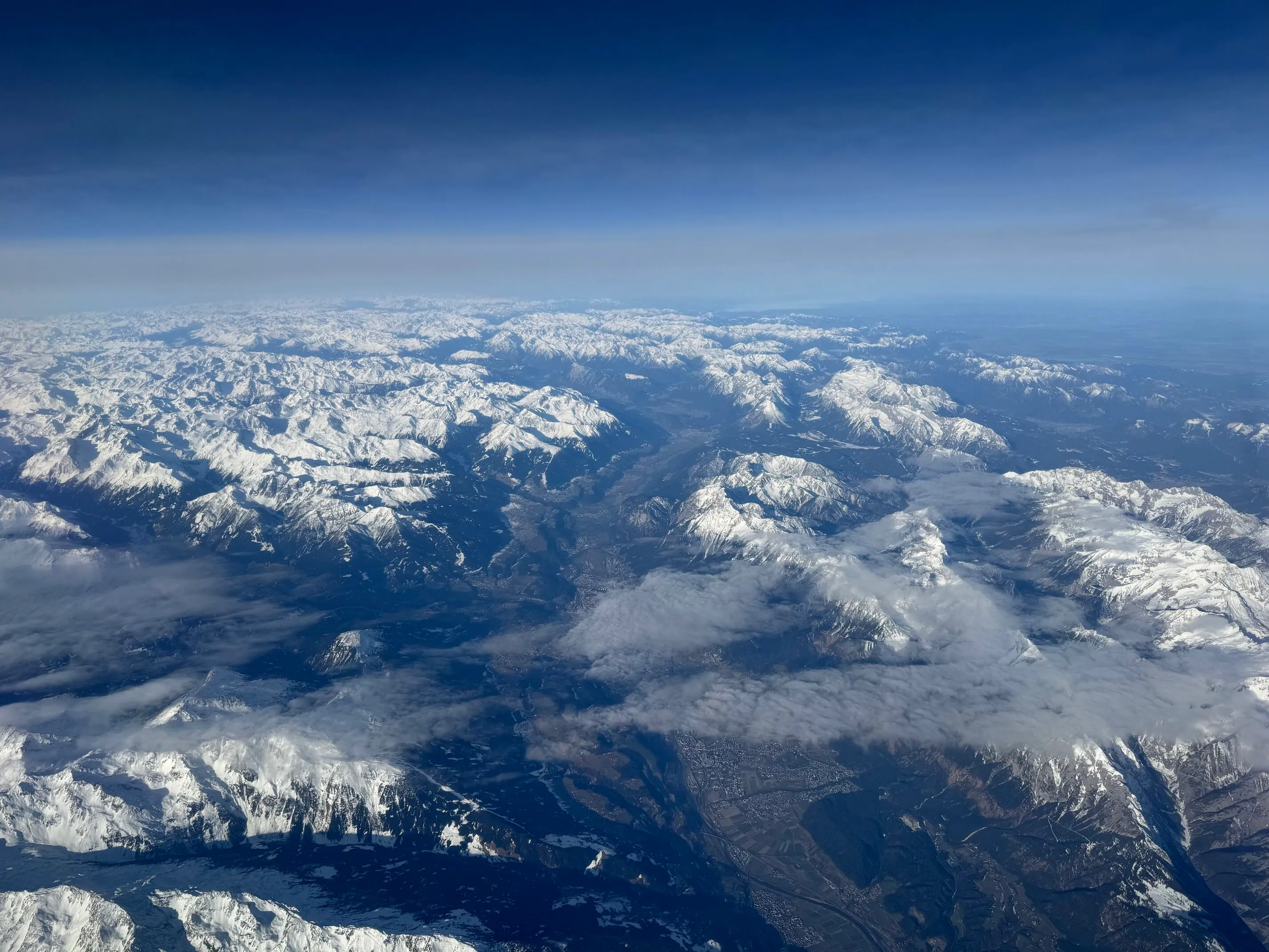 Utsikt over Innsbruck og Alpene fra flyet til Roma på en solværsdag